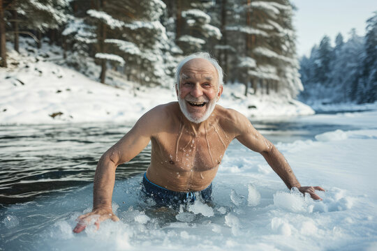 happy elderly gray-haired man bathes in an icy river in winter against the backdrop of a snowy forest