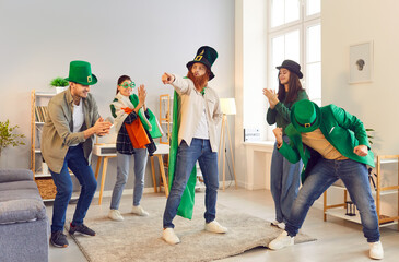 Cheerful group of friends celebrates Saint Patrick Day party at home living room with joyous...