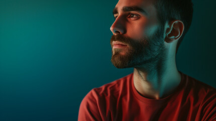 Side profile of a contemplative man with a beard, red shirt, and a moody blue light on the face