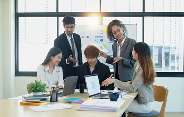Team of asian business working with document paper sitting at desk in office in meeting room, Business team working with project statistics, Asian business team and present graphic info in room.