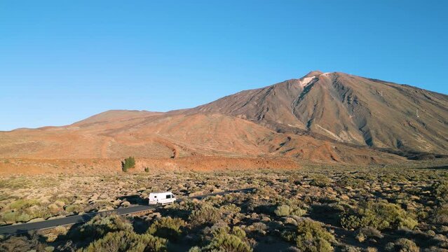 Witness the stunning view of an RV driving in the desert near Teide mountain in Tenerife.