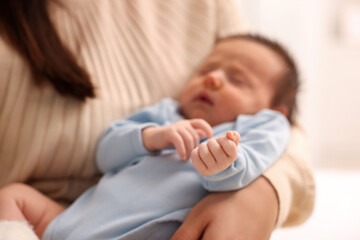 Mother with her sleeping newborn baby on blurred background, selective focus