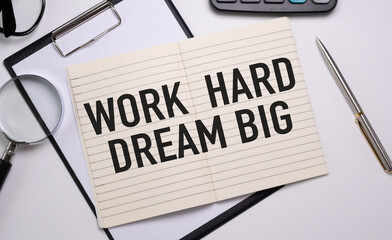 Work hard dream big. Notepad with pen, glasses, calculator, and magnifier on white table.