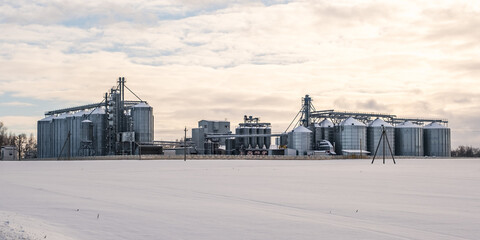 silos and agro-processing plant for processing for drying cleaning and storage and seed preparation complex in snow of winter field © hiv360