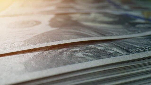 Captivating macro shots of stacks of US one hundred-dollar bills reveal intricate details. Debt and assets concept. Paper money Background. 4K HDR.
