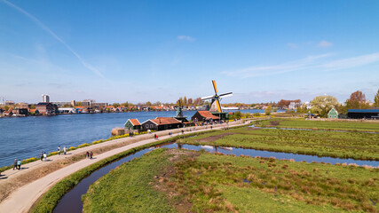 Fototapeta na wymiar Welcome to Holland above a river and the windmills of Zaanse Schans, the Netherlands with its traditional houses, windmills, warehouses and workshops.
