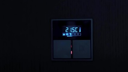 Thermostat on the wall of the room close-up. The man's hand turns off and turns on the light. Person press the button. Sensor of temperature and humidity indicators in the room. Smart system