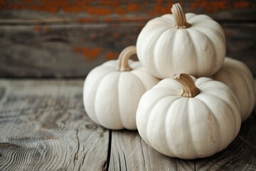 This is a close up photo of three white pumpkins on a wood table background. 