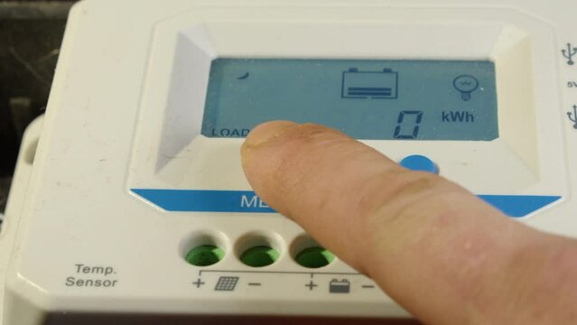 Index finger scrolls through screen views on solar power controller
