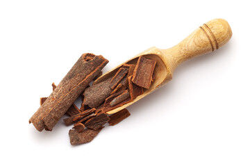 Top view of Organic Cinnamon sticks (Cinnamomum verum), in a wooden scoop. Isolated on a white...