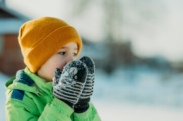 Boy wearing mitten and warming hands in winter
