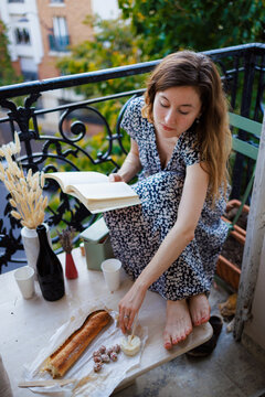 Woman holding book and having food in balcony