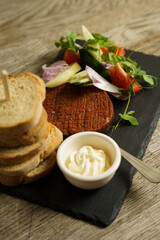 Slice of meat with vegetables and baguette on a plate