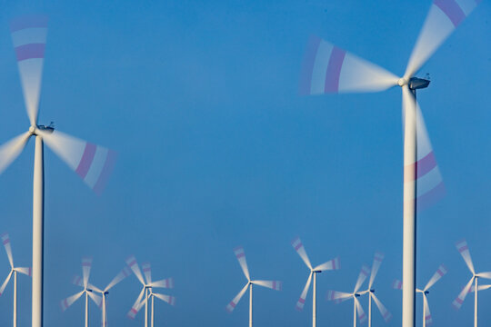 Wind farm turbines spinning against blue sky