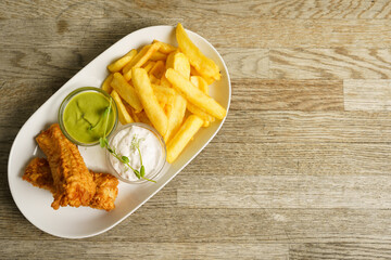 Fish and chips with tartare sauce on wooden table