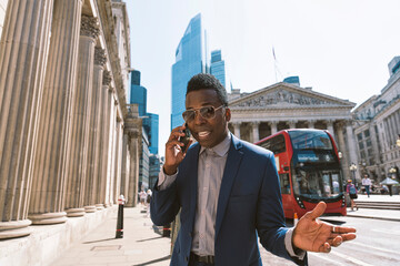 Mature businessman gesturing and talking on smart phone in London city