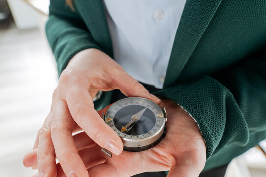 Businesswoman holding compass in hand at office