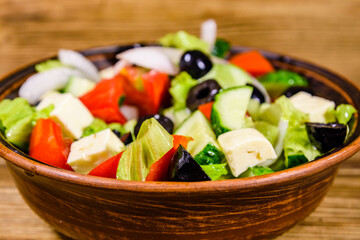 Ceramic plate with greek salad on wooden table