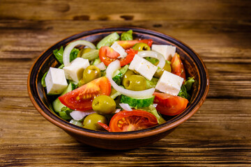 Ceramic plate with greek salad on wooden table
