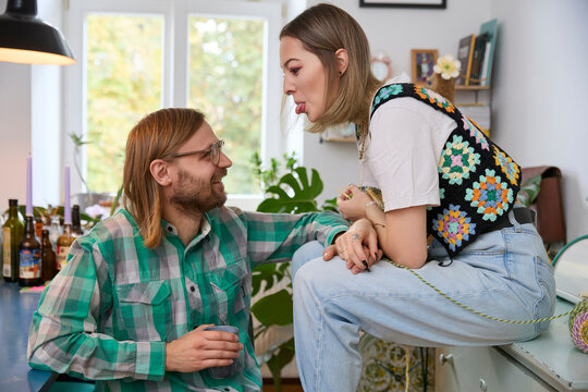 Woman teasing happy man sitting at home