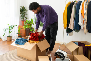 Young man doing decluttering of clothes at home