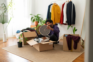 Young man organizing clothes and objects in cardboard boxes