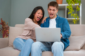 Happy multiethnic man and woman have fun browsing internet on laptop. Technology concept.