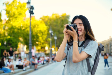 Taiwanese male tourist smiling and taking photos with a camera while sightseeing in Madrid, Spain.