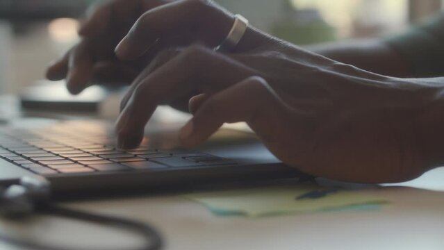 Close up view of hands of hands of unrecognizable man typing on laptop keyboard at workplace in office