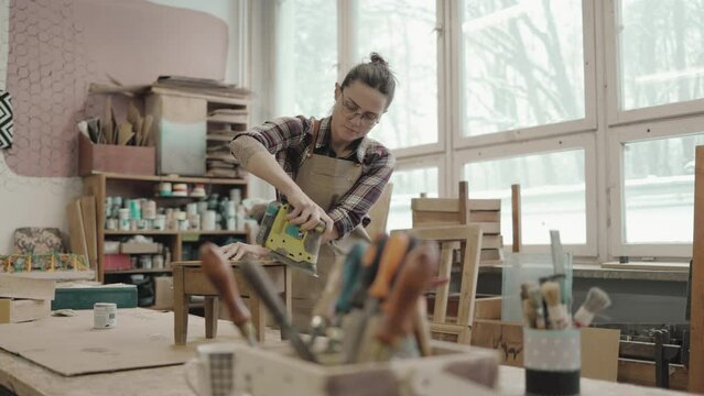 Woman working with sander at carpentry workshop
