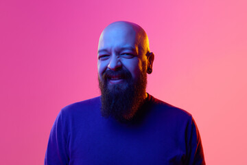Gel portrait of bearded bald man in his 30s wearing blue sweater, looking in camera and laughing...
