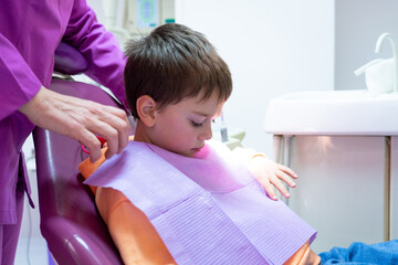 Boy at the dentist putting on disposable dental bib