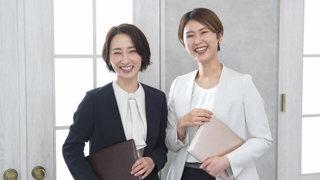 立ちながら話をするジャケットを着た女性2人