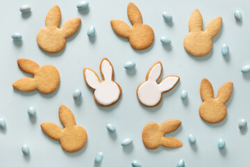 Easter cookies shaped of bunny and chocolate eggs on blue background. View from above. Festive food and kids snacks. Holiday Easter pattern.