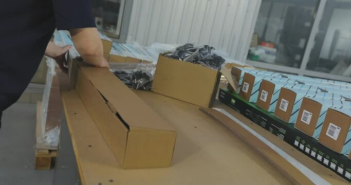 A woman packer packs a product into a box. Packing the goods in a box. Packer work in a factory