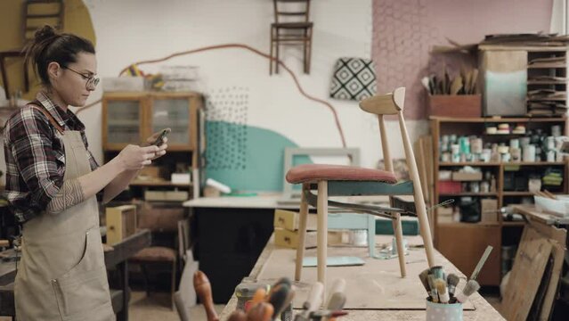 Craftswoman taking photos of a renovated chair in her workshop