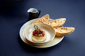 Baked camembert with berries and nuts in a plate. Photo for the menu