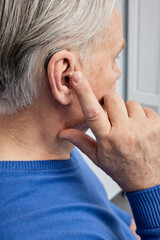 Obraz premium Senior man can hear sounds with hearing aid behind-the-ear. Hearing loss treatment at older people