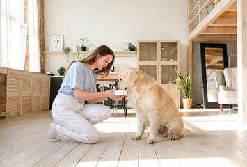 Portrait of happy young woman with pet dog, sitting on floor at home. Caucasian female hugging...