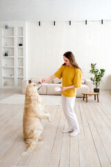 Portrait of happy young woman with pet dog, sitting on floor at home. Caucasian female hugging...