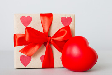 gift box with red bow and red heart on colored background. Perspective view. Flat lay
