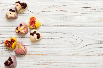 chocolate sweets in the form of a heart with fruits and nuts on a colored background. top view with space for text, holiday concept