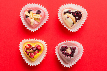 chocolate sweets in the form of a heart with fruits and nuts on a colored background. top view with space for text, holiday concept