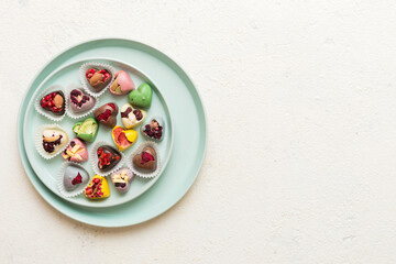 Plate with different chocolate on colored background. Assortment of fine chocolates top view vith copy space Health and obesity concept
