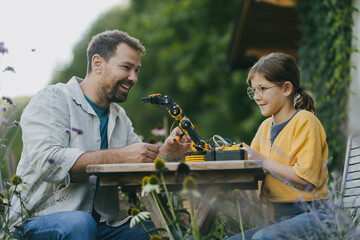 Father supporting daughter in pursuing robotics, science, IT technologies and programming. Concept...