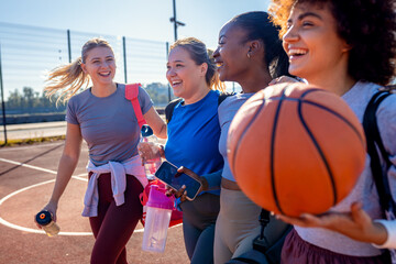Diverse group of young woman walking on basketball court preparing to play.