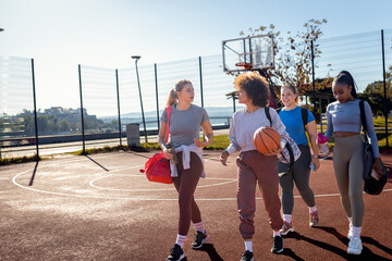 Diverse group of young woman walking on basketball court preparing to play.