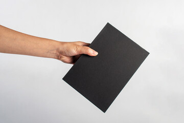 Blank black book cover in hand on white background.