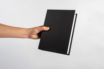 Blank black book cover in hand on white background.