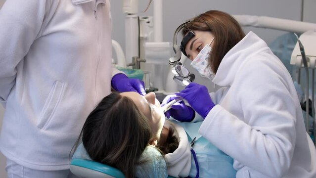 A young woman is undergoing treatment in a modern dental clinic. The concept of dental treatment, whitening, installation of veneers and braces, cleaning the oral cavity.